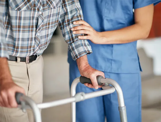 Nurse assisting older man with walker