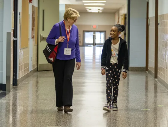 Older woman walking down hall with young girl